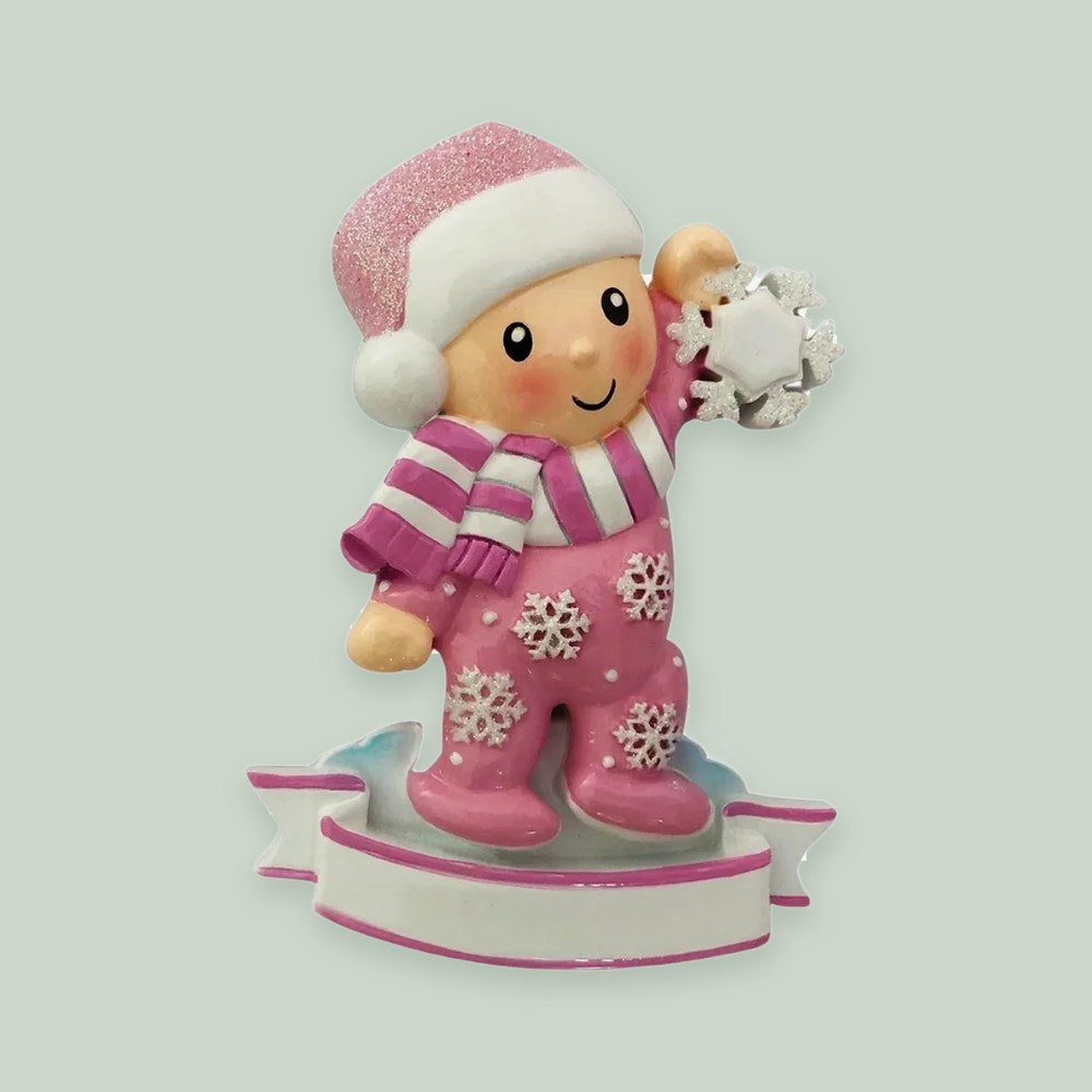 Baby Girl In Pajamas Holding Snowflake-Pink ornament on a sage green background