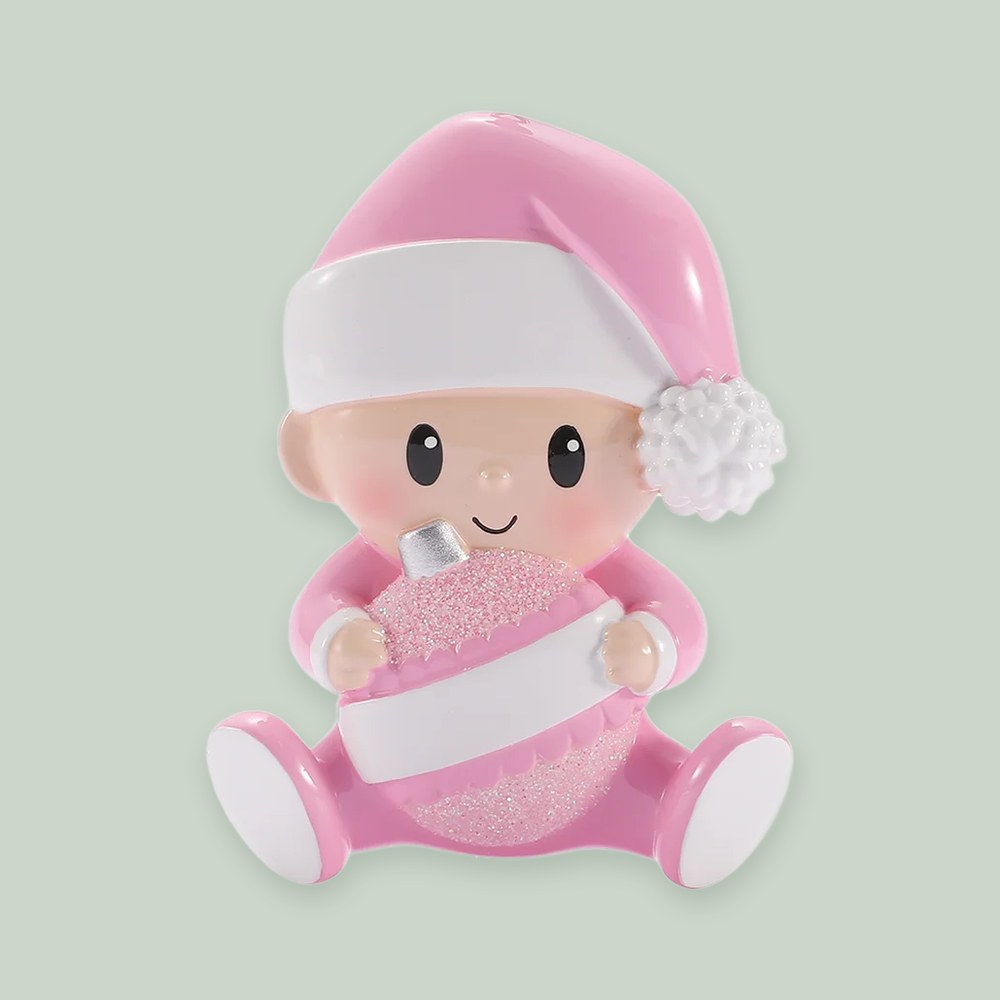 Baby Holding Christmas Bauble — Pink ornament on a sage green background