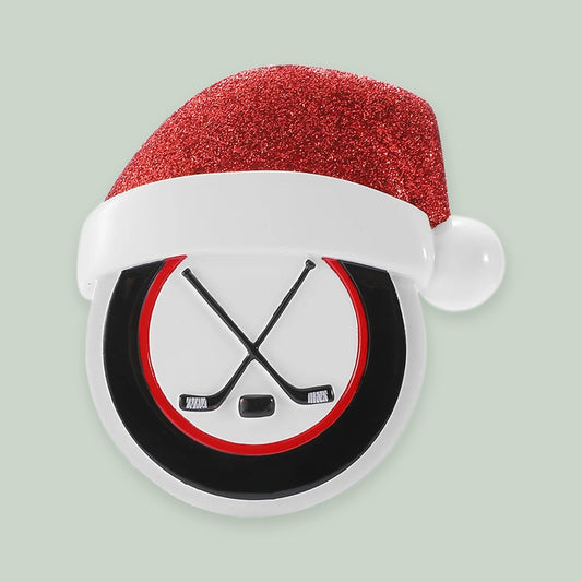Hockey Puck with Santa Hat ornament on a sage green background